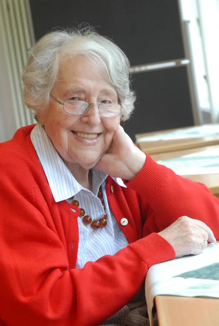 Die Stifterin - Foto zeigt Elfriede Eilers, eine gepflegt, gut aussehende älter Dame mit weißem Kurzhaarschnitt. Sie lächelt und schaut zum Betrachter oder zur Betrachterin. Sie trägt eine rote Strickjacke